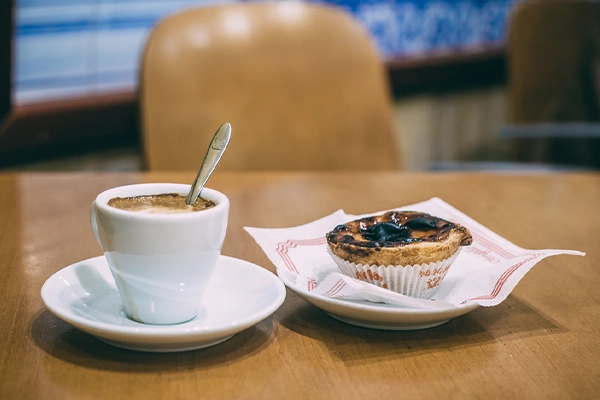 Tradional Pastel de nata, portuguese traditional creamy pastry and coffee on cafe bar. Traditional portuguese afternoon snack