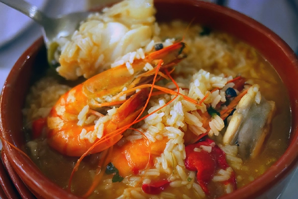 Selective focus, Close up authentic traditional Portuguese seafood soup with rice, arroz de marisco in red bowl
