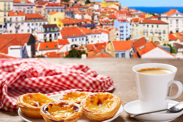 cup of coffee and plate of traditional portuguese pastries - Pastel de nata, over Alfama district, lisbon, Portugal
